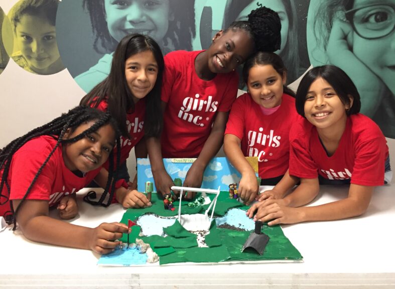 group of girls facing camera smiling working on a project