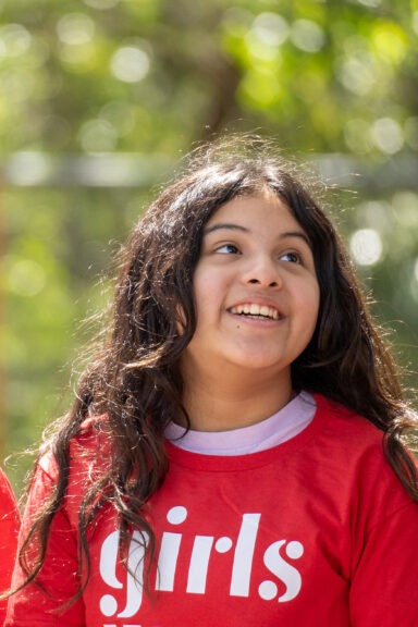 girl smiling in red girls inc. t-shirt